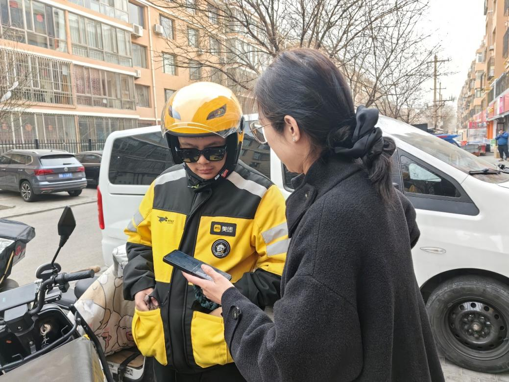 社區(qū)工作人員在外賣站點(diǎn)了解騎手需求并邀請騎手加入社區(qū)志愿服務(wù)群。青山區(qū)萬青路街道辦事處供圖